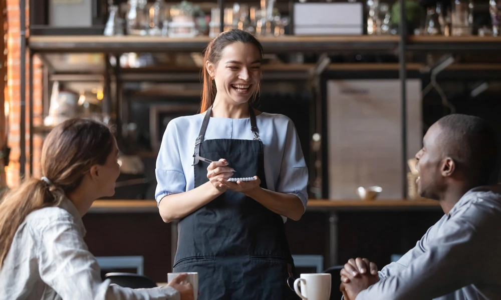 Une serveuse prenant la commande d’un couple dans un restaurant