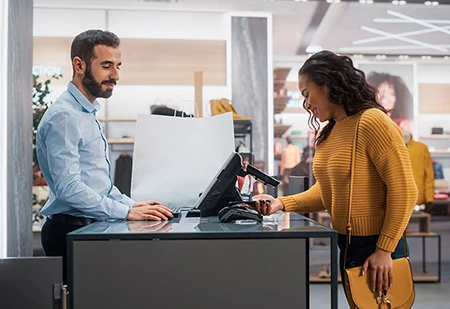 Une femme finalisant ses achats à la caisse d’un magasin avec son téléphone